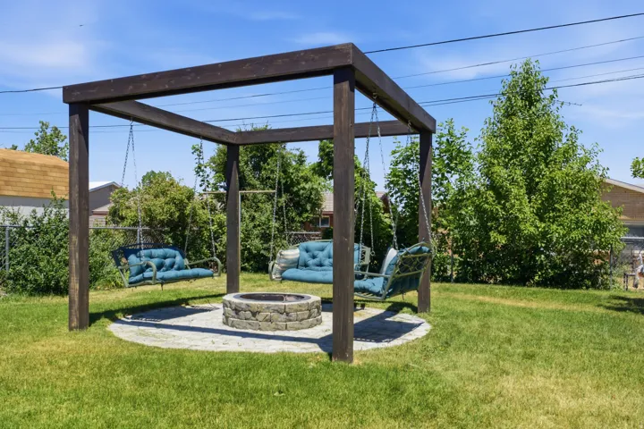 Backyard entertainment area featuring a wood-beam pergola with three suspended swing seats