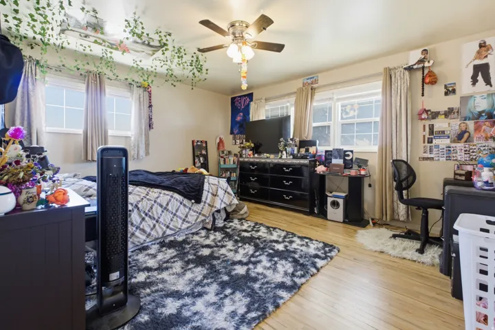 Bedroom featuring light wood-finish flooring and multiple windows with curtain treatments