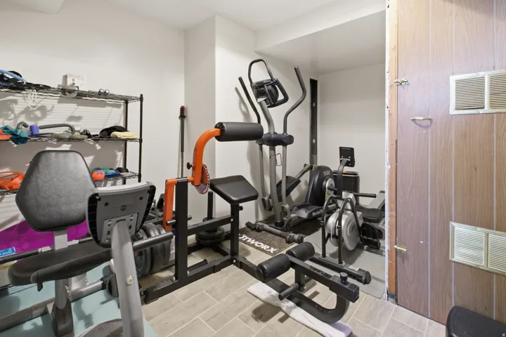 Dedicated fitness area featuring light-toned walls and wood-finish flooring
