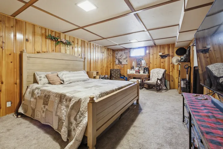 Spacious room featuring wood paneling, a grid-patterned ceiling, recessed lighting, and carpeted flooring
