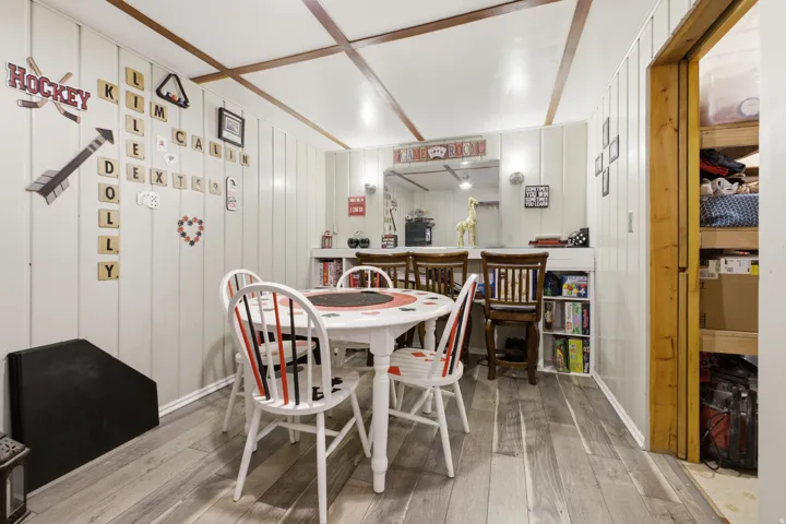 Recreational room featuring wood-finish flooring, vertical paneling, and a wood beam ceiling