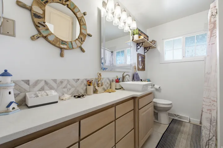 Bathroom featuring a floating vanity with wood-finish cabinetry, a vessel sink, and a stone countertop