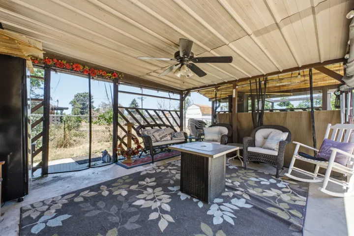 Covered outdoor patio featuring a ceiling fan, concrete flooring, and an open perimeter