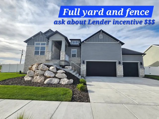 Two-car garage, stone and siding exterior, concrete driveway, front yard landscaping with rock features, and a concrete pathway