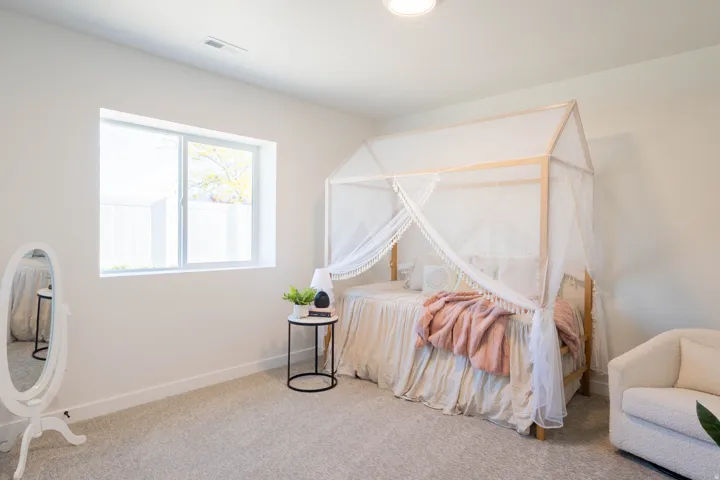 Recessed lighting illuminates a room featuring light-toned walls and plush carpeting