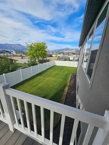 Spacious backyard featuring a manicured lawn, full vinyl privacy fencing, and a surrounding planter bed