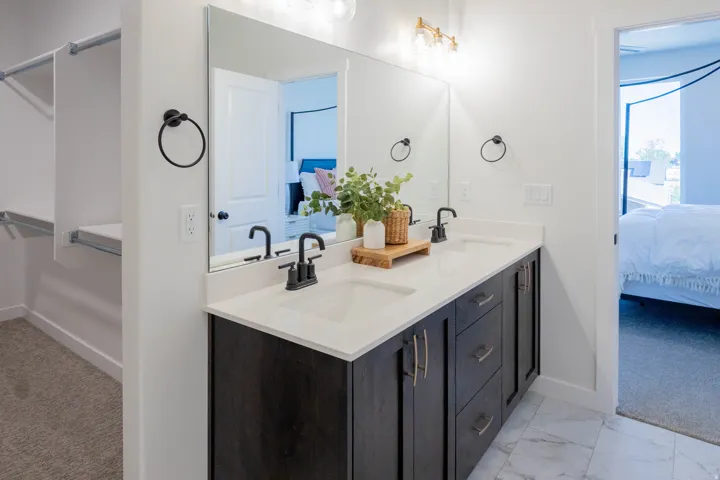 Bathroom featuring a dual vanity with dark wood-finish cabinetry, white countertop, and contemporary black fixtures