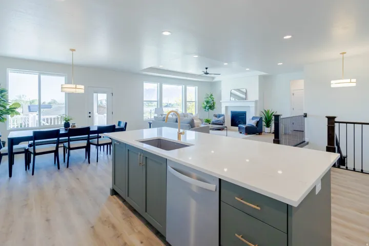 Kitchen island with integrated stainless steel dishwasher, quartz countertop, and gold-finish faucet