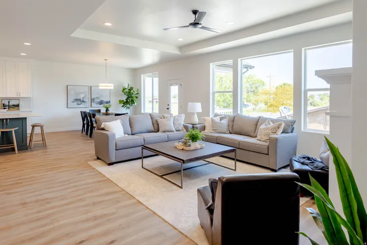 Open-concept living space featuring wood-finish flooring, recessed lighting, and a tray ceiling with a ceiling fan