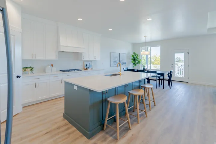 Open-concept kitchen with a large central island, white shaker cabinetry, and wood-finish flooring