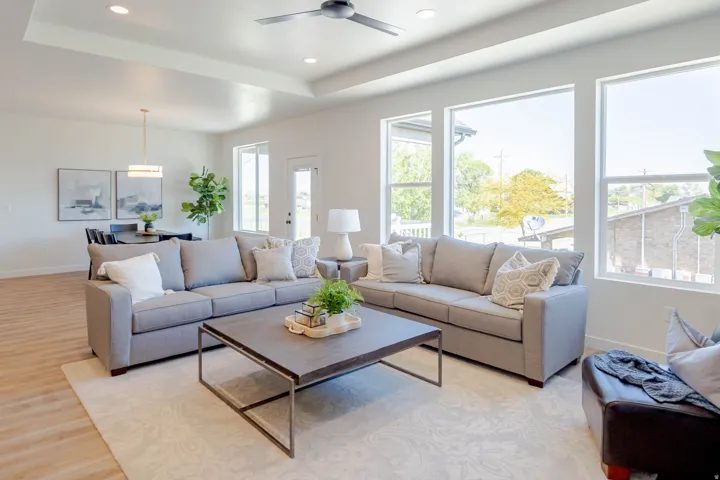Spacious living area featuring a tray ceiling with recessed lighting, wood-finish flooring, and multiple large windows