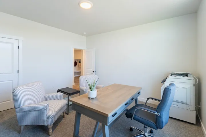 Recessed ceiling lighting illuminates a room featuring light-toned walls and carpet flooring