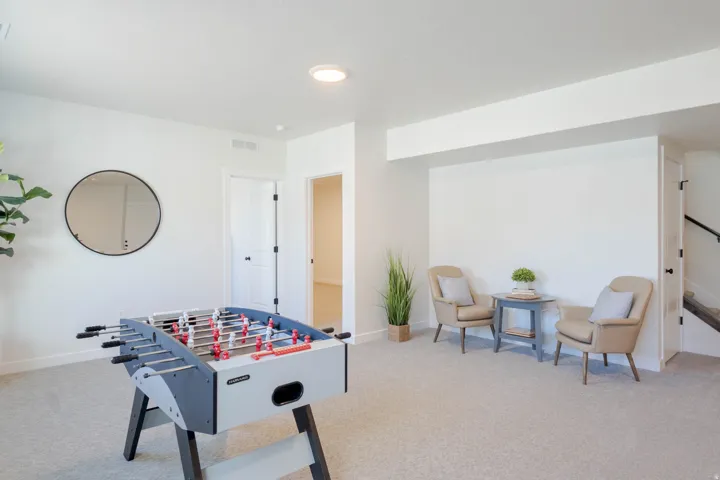Spacious recreational room featuring light-toned carpeting, recessed ceiling lighting, and a neutral color palette