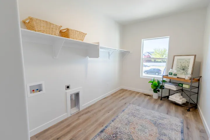 Bright utility room featuring wood-finish flooring, a single window, and a built-in shelf system