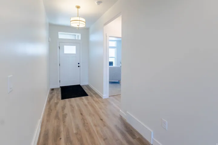 Entryway featuring wood-finish flooring, a white front door with a transom window, and a drum-style ceiling light