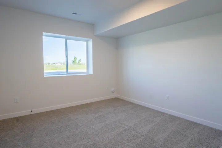 Carpeted interior space with a single window and white trim