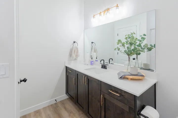 Dark wood-finish vanity with gold-tone hardware, white countertop, and integrated rectangular sink