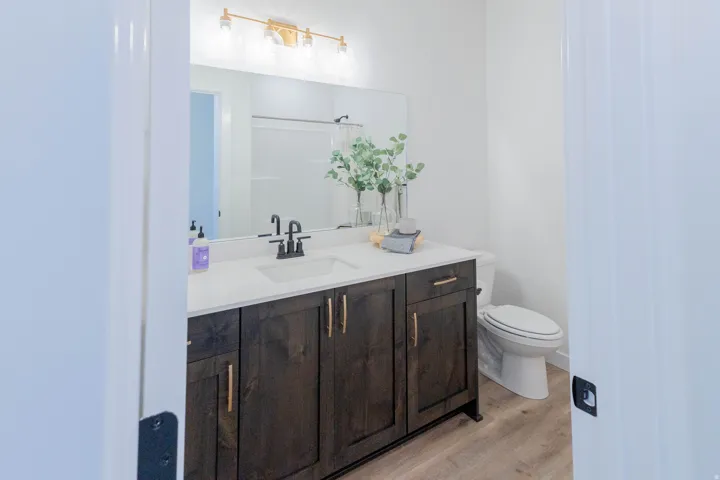 Bathroom featuring a dark wood-finish vanity with a white countertop, undermount sink, and matte black faucet