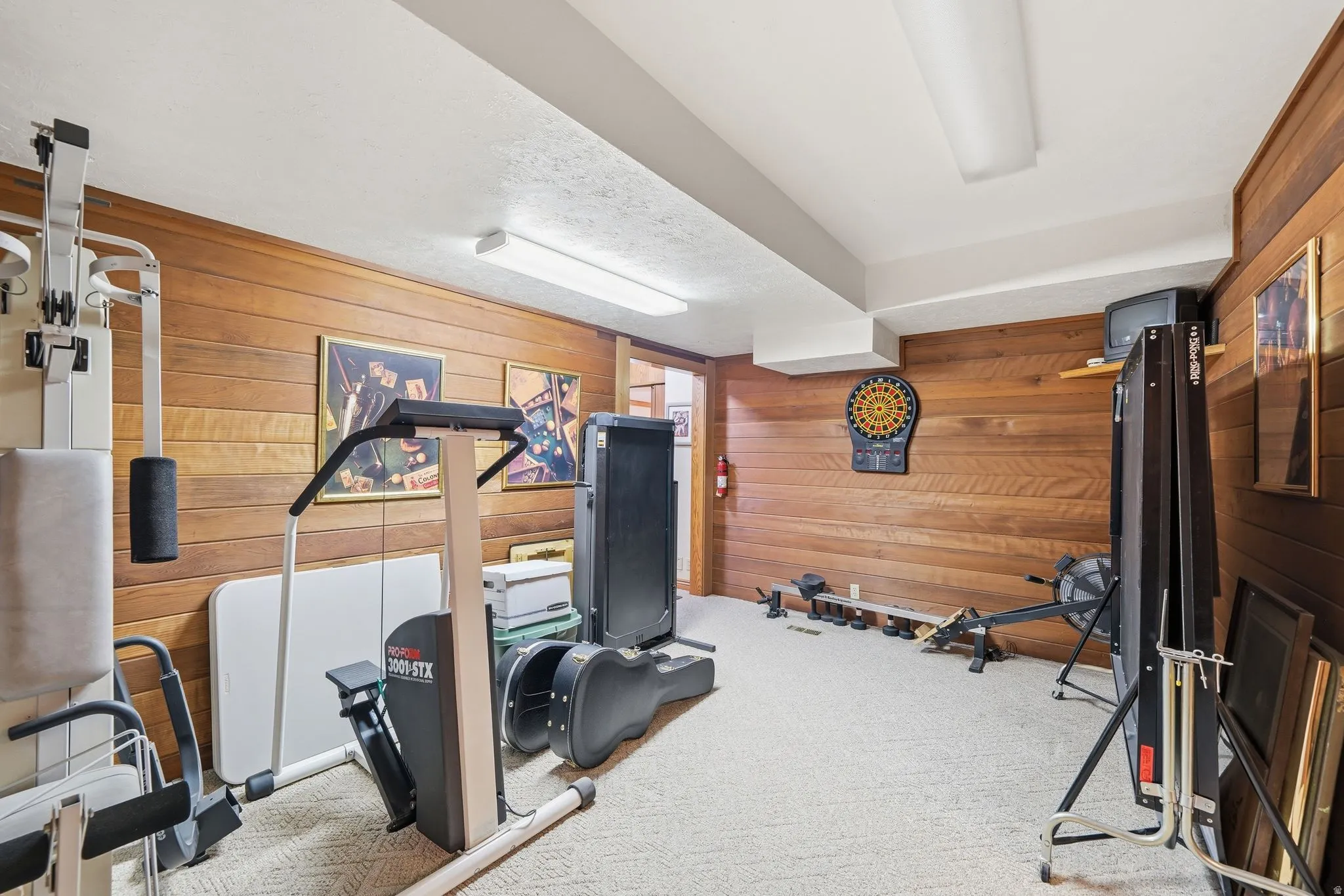 Spacious room with wood-finish paneling, white ceiling, and light-colored carpet flooring