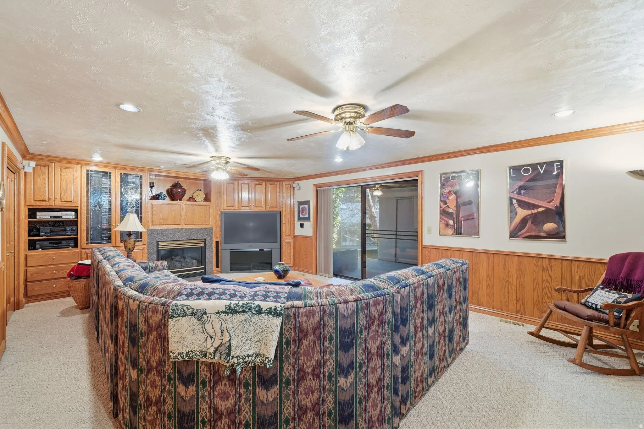 Carpeted recreation room featuring a built-in media center with a fireplace, wood-finish cabinetry, and glass patio doors