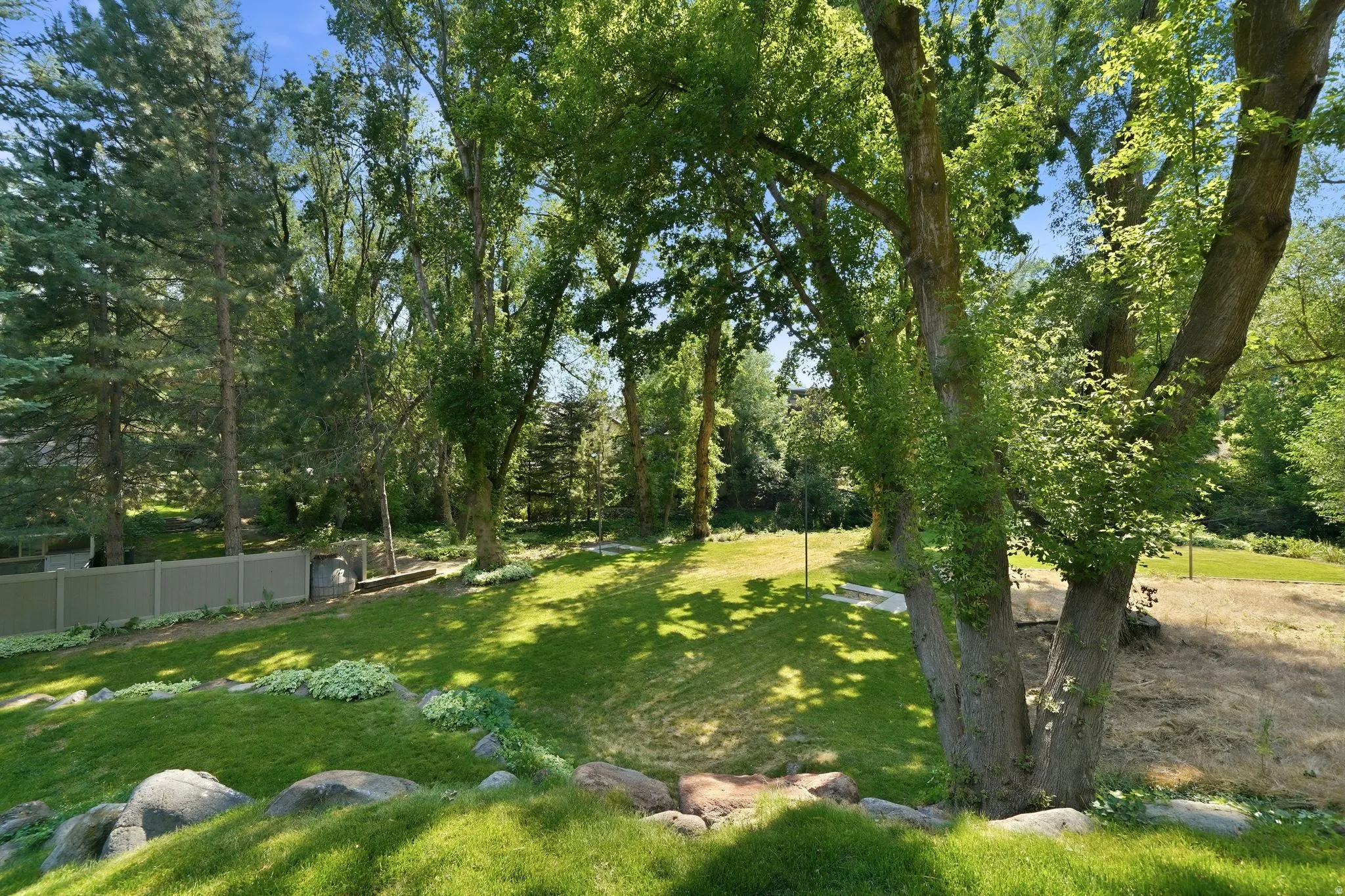 Expansive green lawn with mature trees and natural rock landscaping