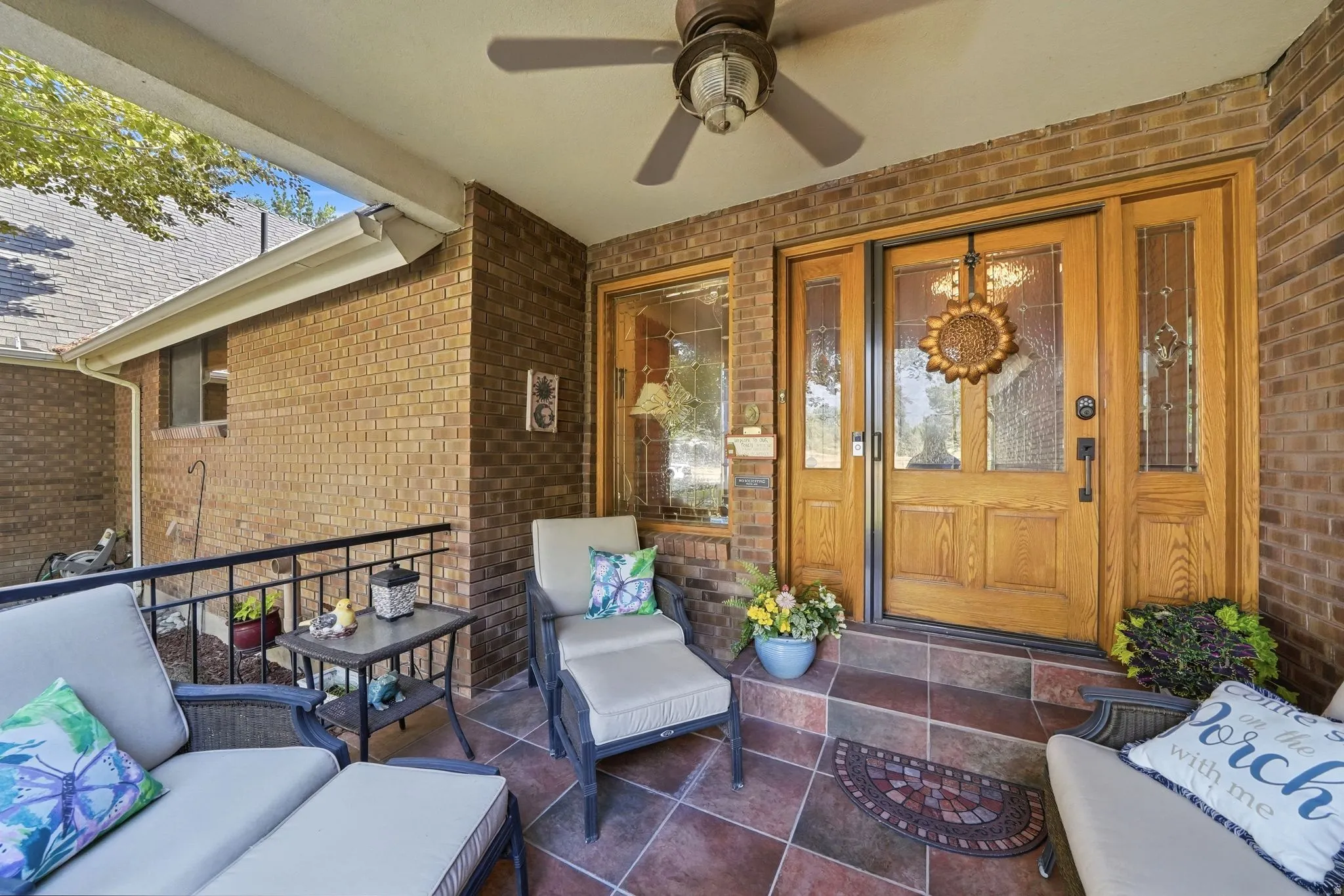 Covered front porch featuring a brick exterior and a ceiling fan
