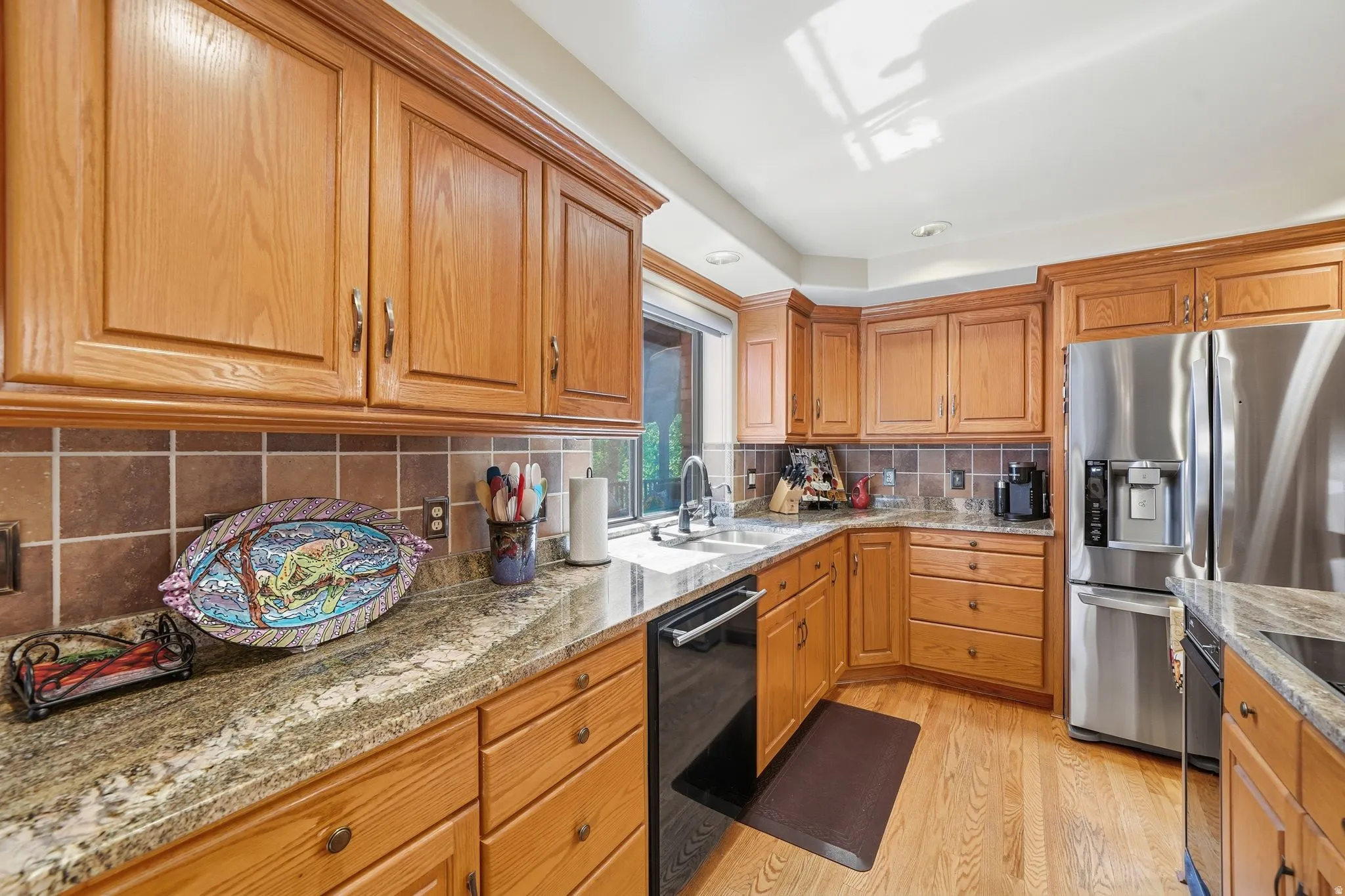 Kitchen featuring natural wood cabinetry, light-toned wood-finish flooring, and a window above the sink