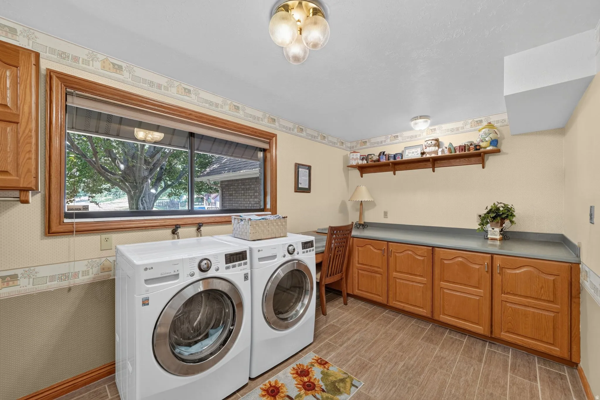 Laundry area featuring wood-finish flooring, a large window with wood trim, and extensive built-in cabinetry with a grey countertop