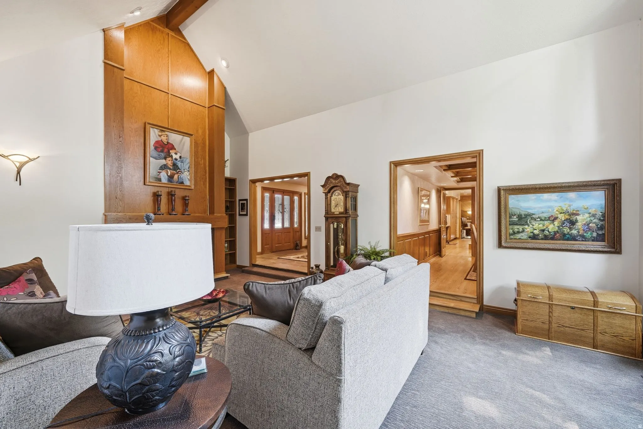 Carpeted living area featuring a vaulted ceiling with exposed wood beams and recessed lighting