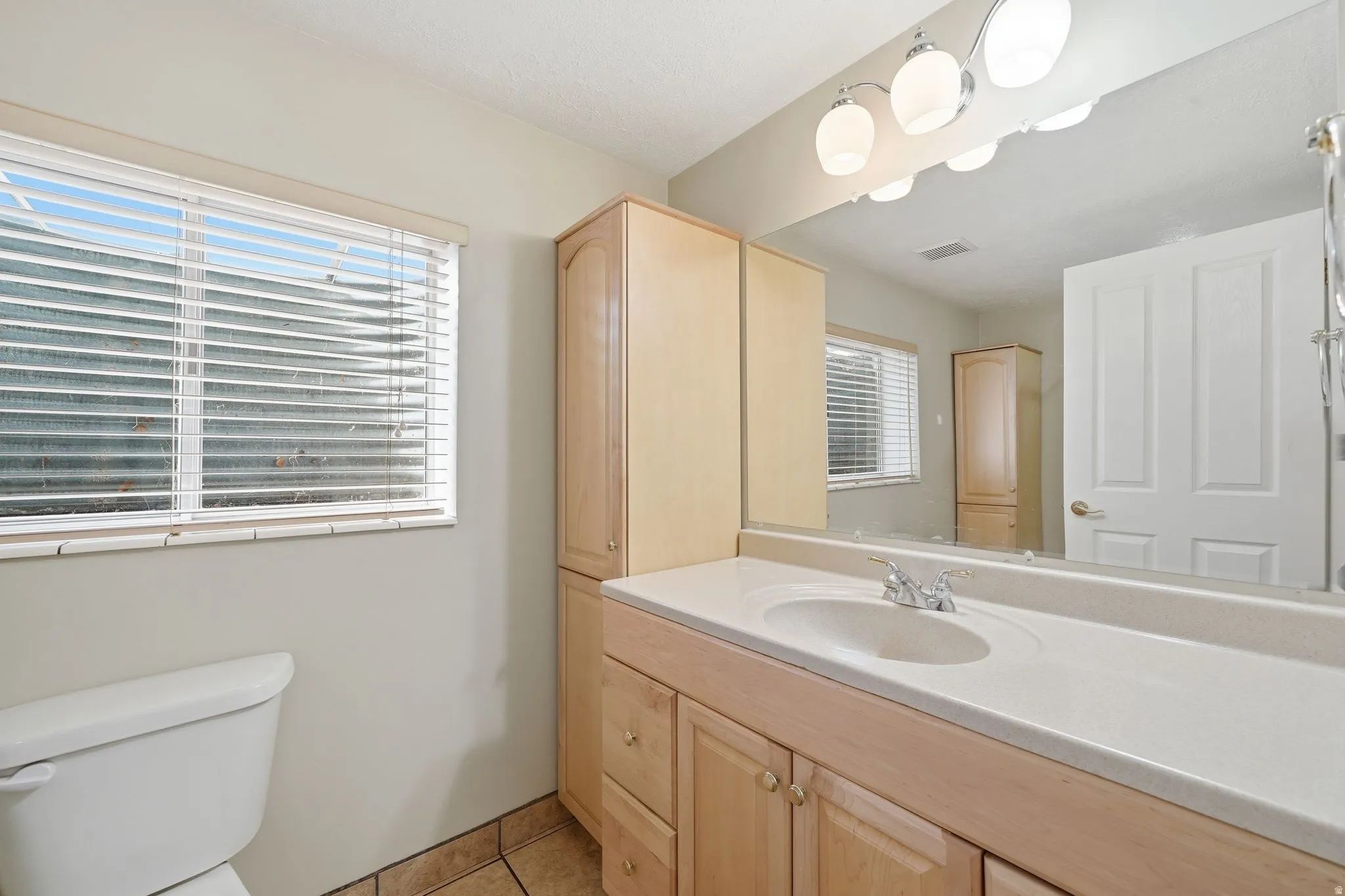Bathroom vanity with a light countertop, a single basin sink, and a chrome faucet