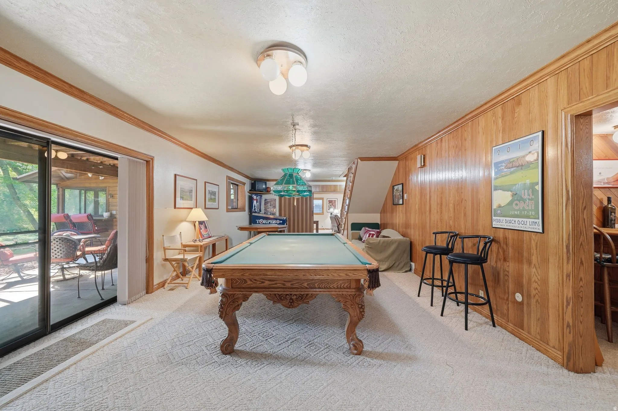 Recreation room featuring full wood paneling, recessed lighting, and access to an enclosed patio