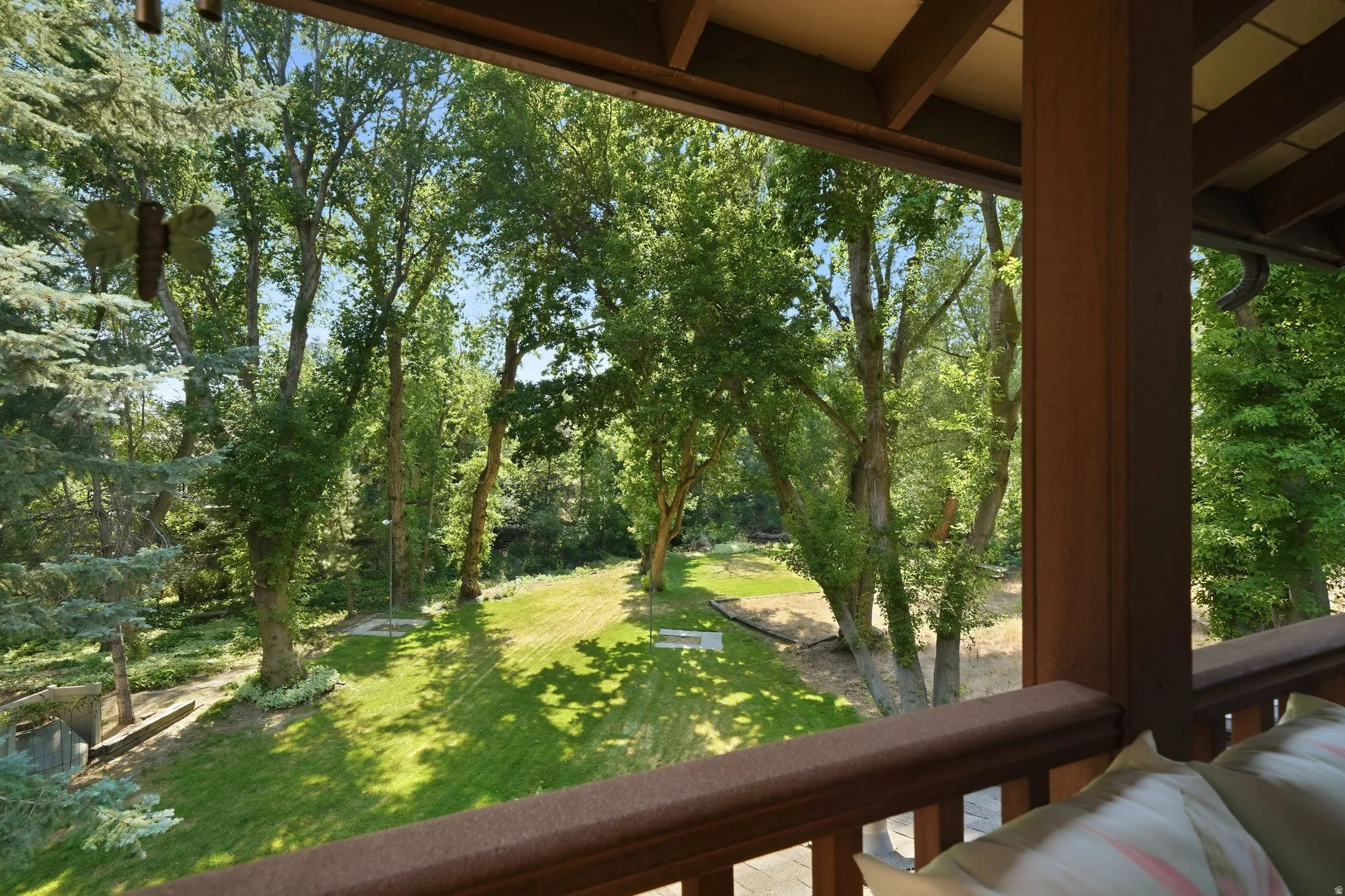 Expansive backyard featuring a large manicured lawn, mature deciduous trees, and evergreen trees