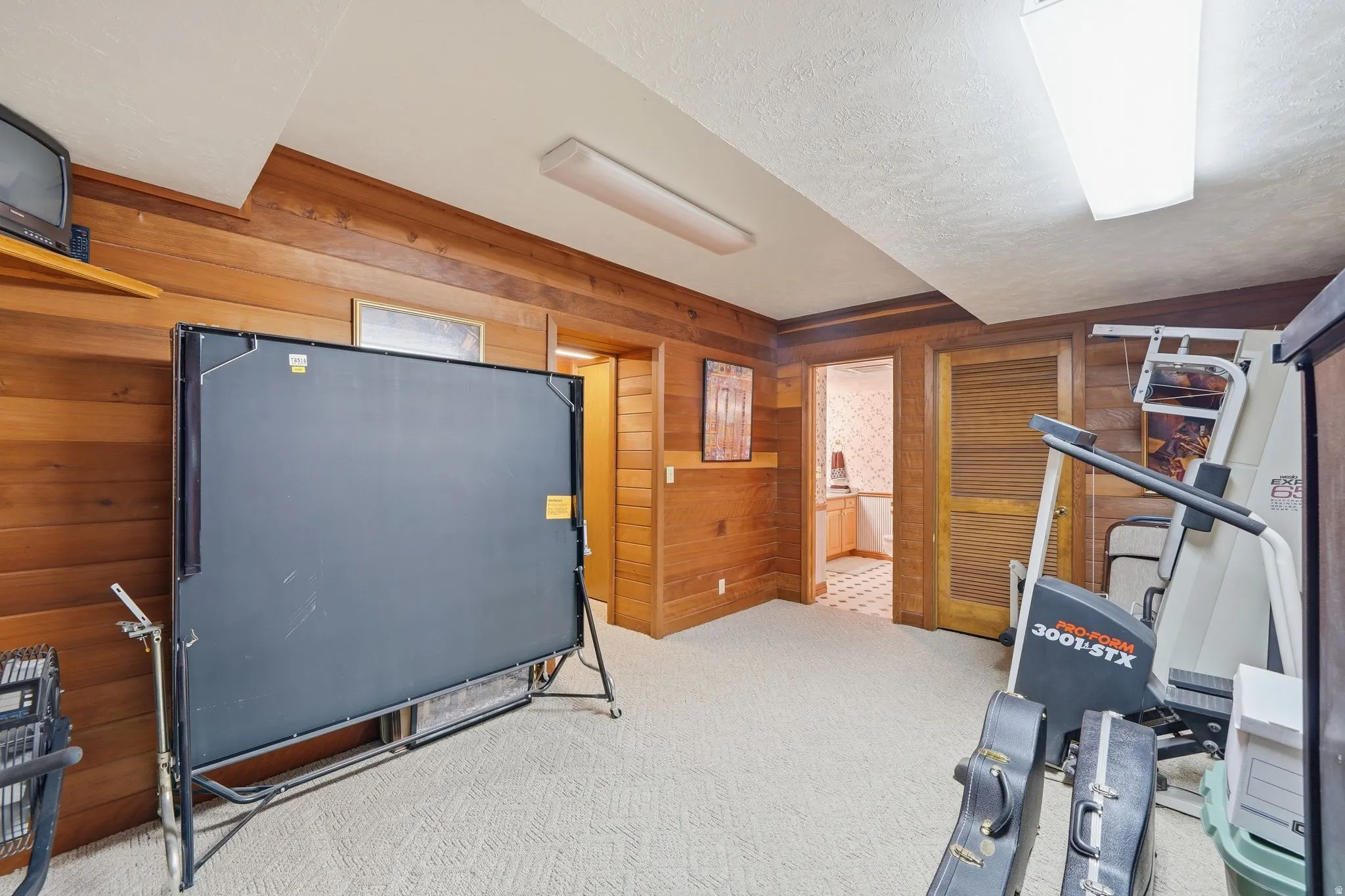 Carpeted room with wood paneling, recessed lighting, and a textured ceiling