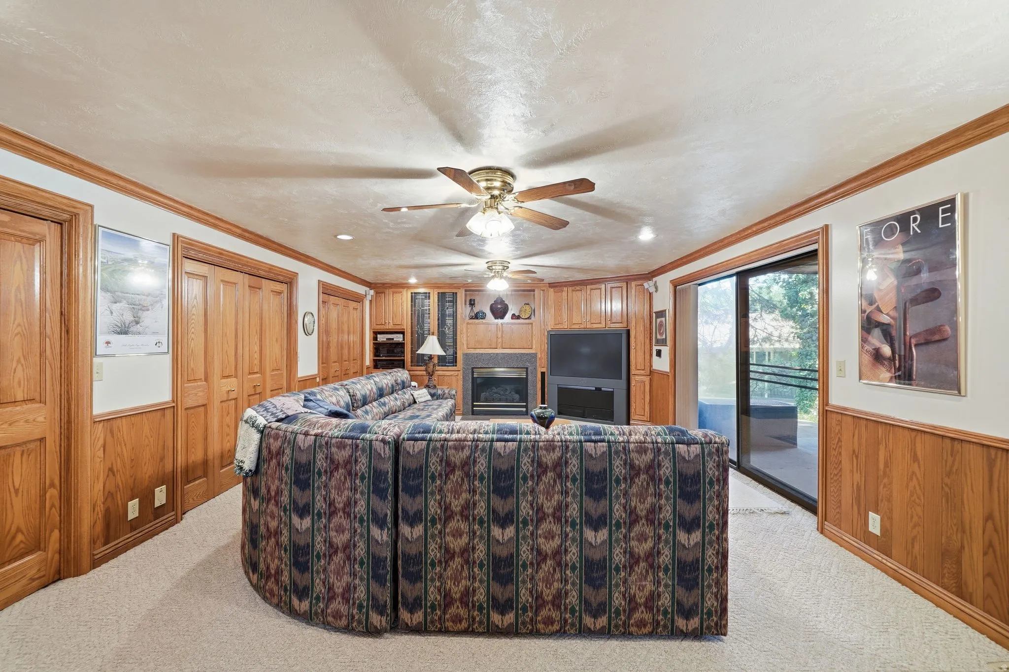 Lower-level living area featuring wood paneling, built-in cabinetry, a fireplace, and direct access to an outdoor patio via sliding glass doors