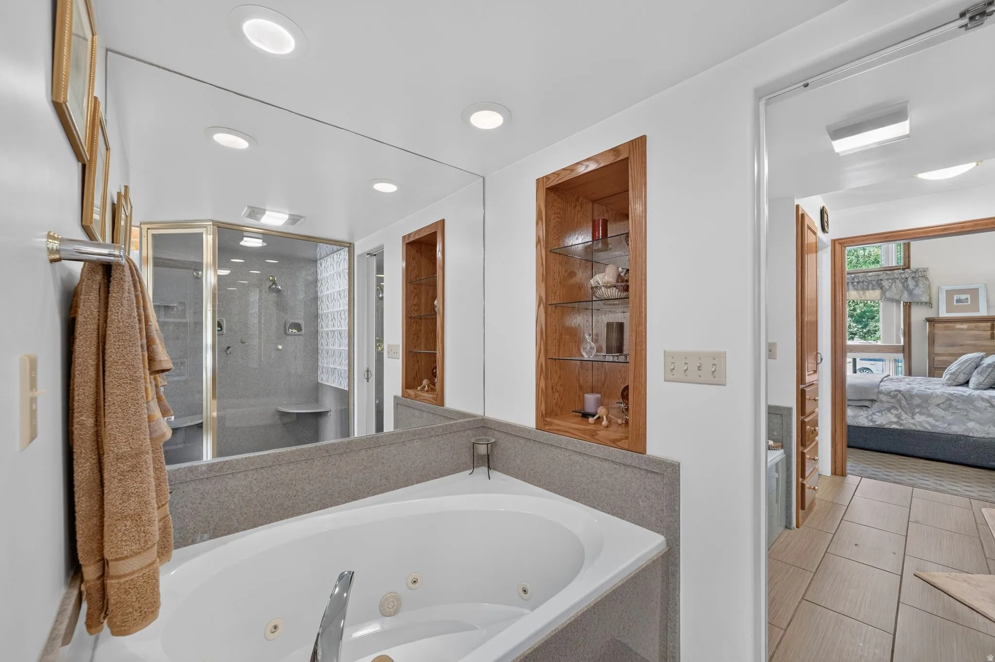 Bathroom featuring a jetted tub, an expansive wall mirror, and recessed lighting