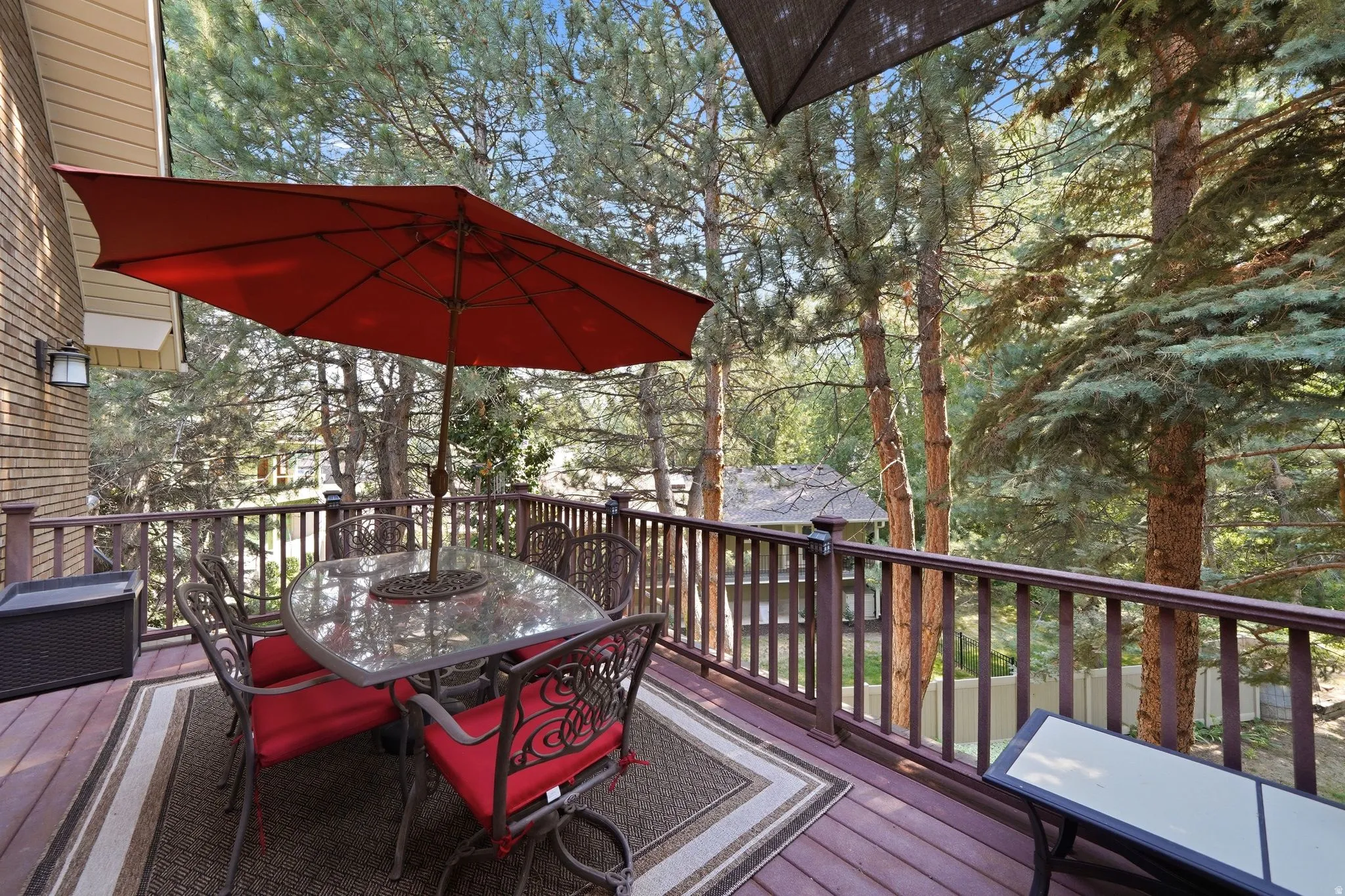 Spacious elevated deck featuring wood-finish flooring, a full railing system, and a brick exterior wall