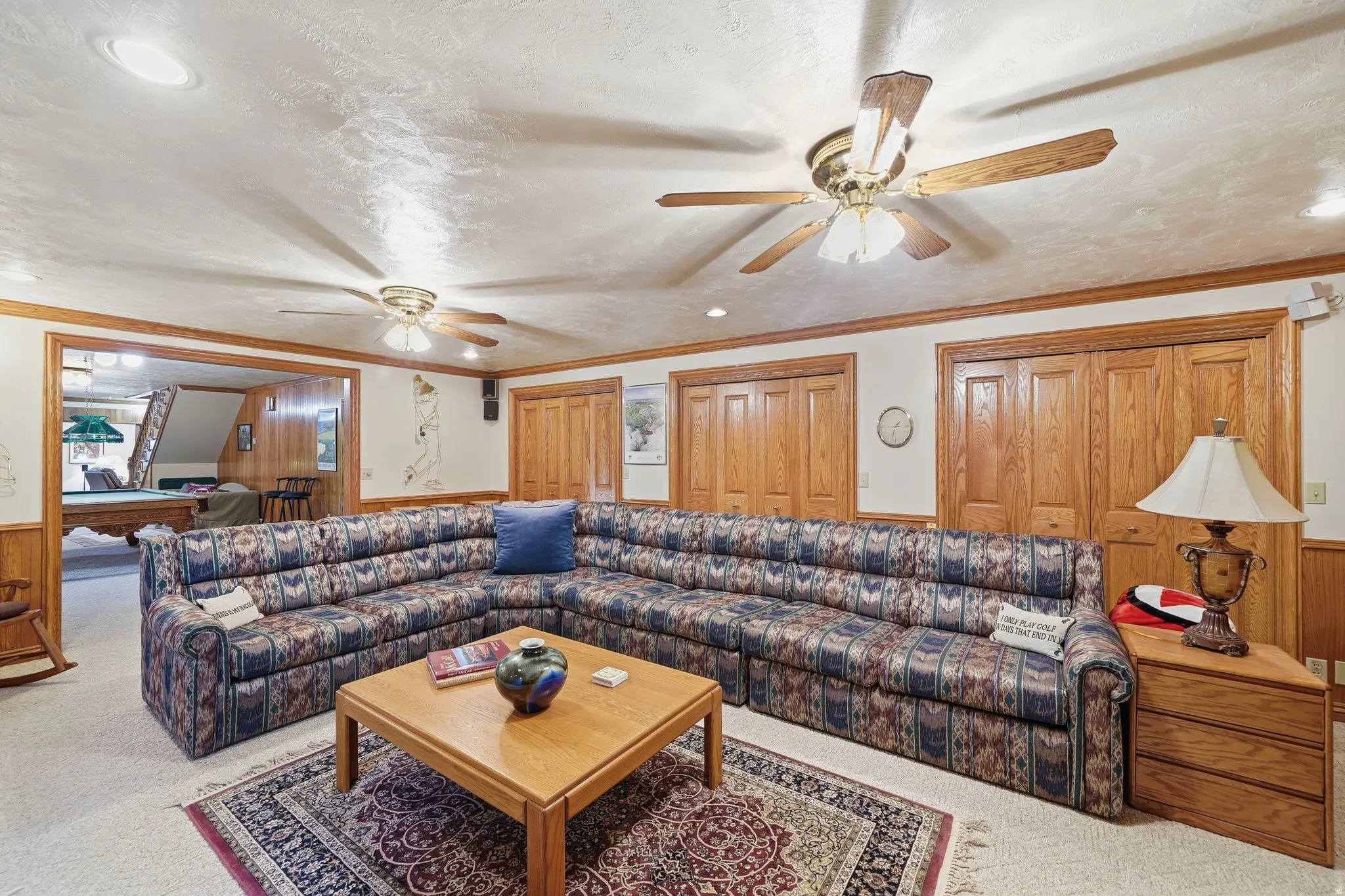 Carpeted recreation room featuring wood trim, ceiling fans, and recessed lighting