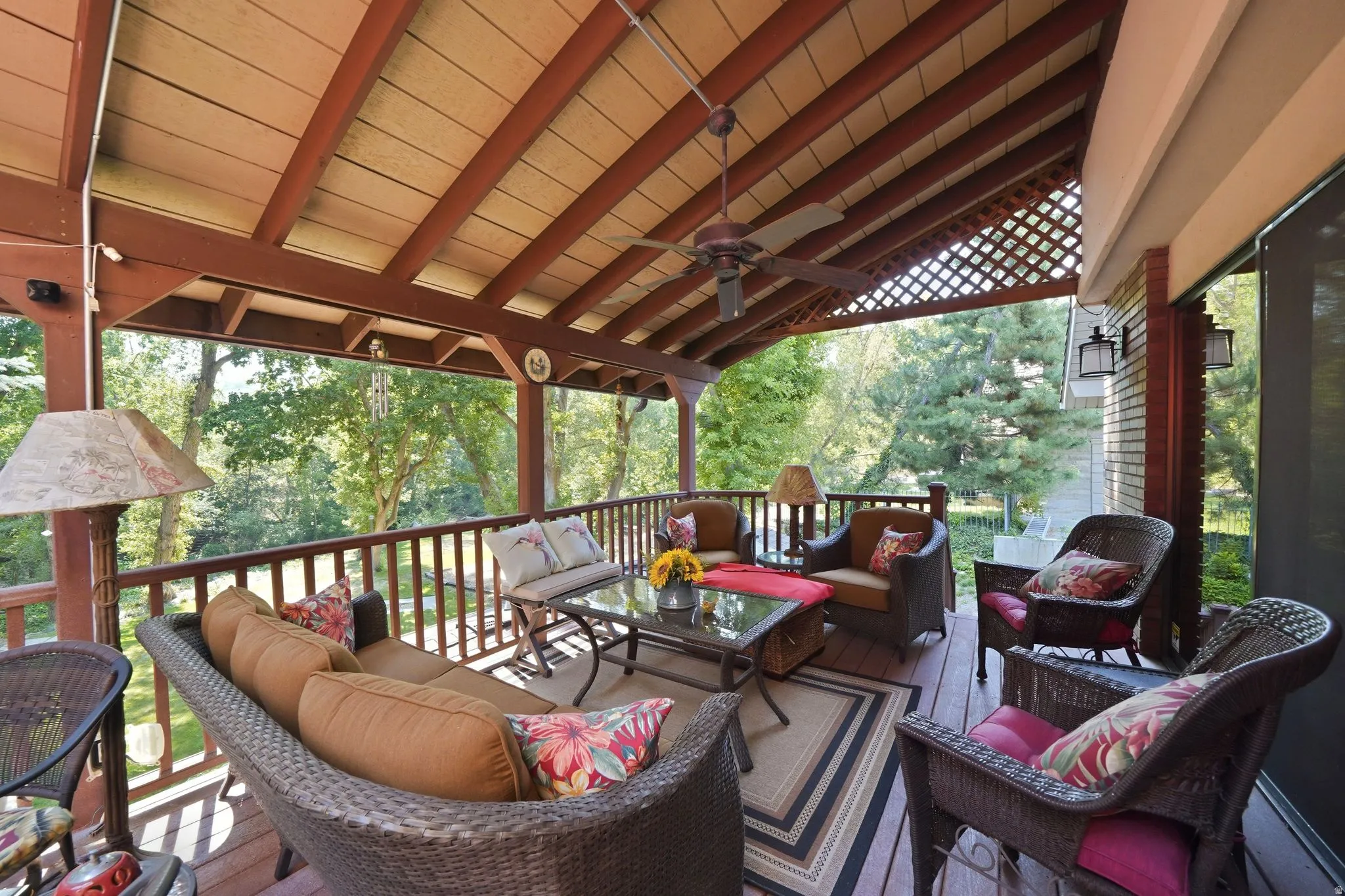 Expansive covered wood deck featuring a slatted ceiling, exposed beams, and a ceiling fan