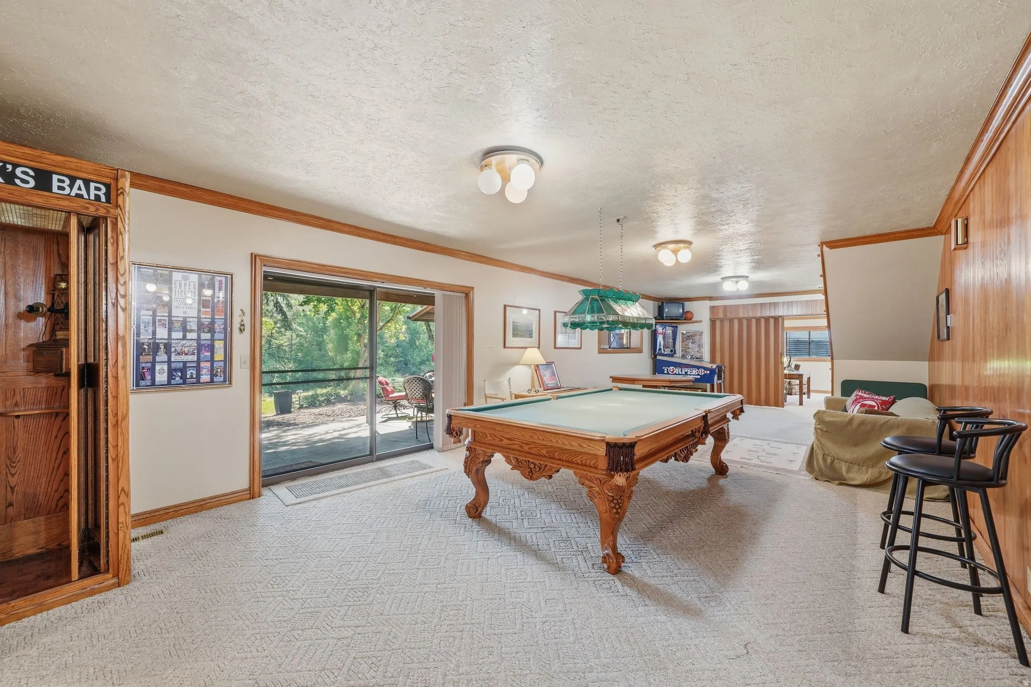Recreation room featuring light-toned patterned carpet and wood trim