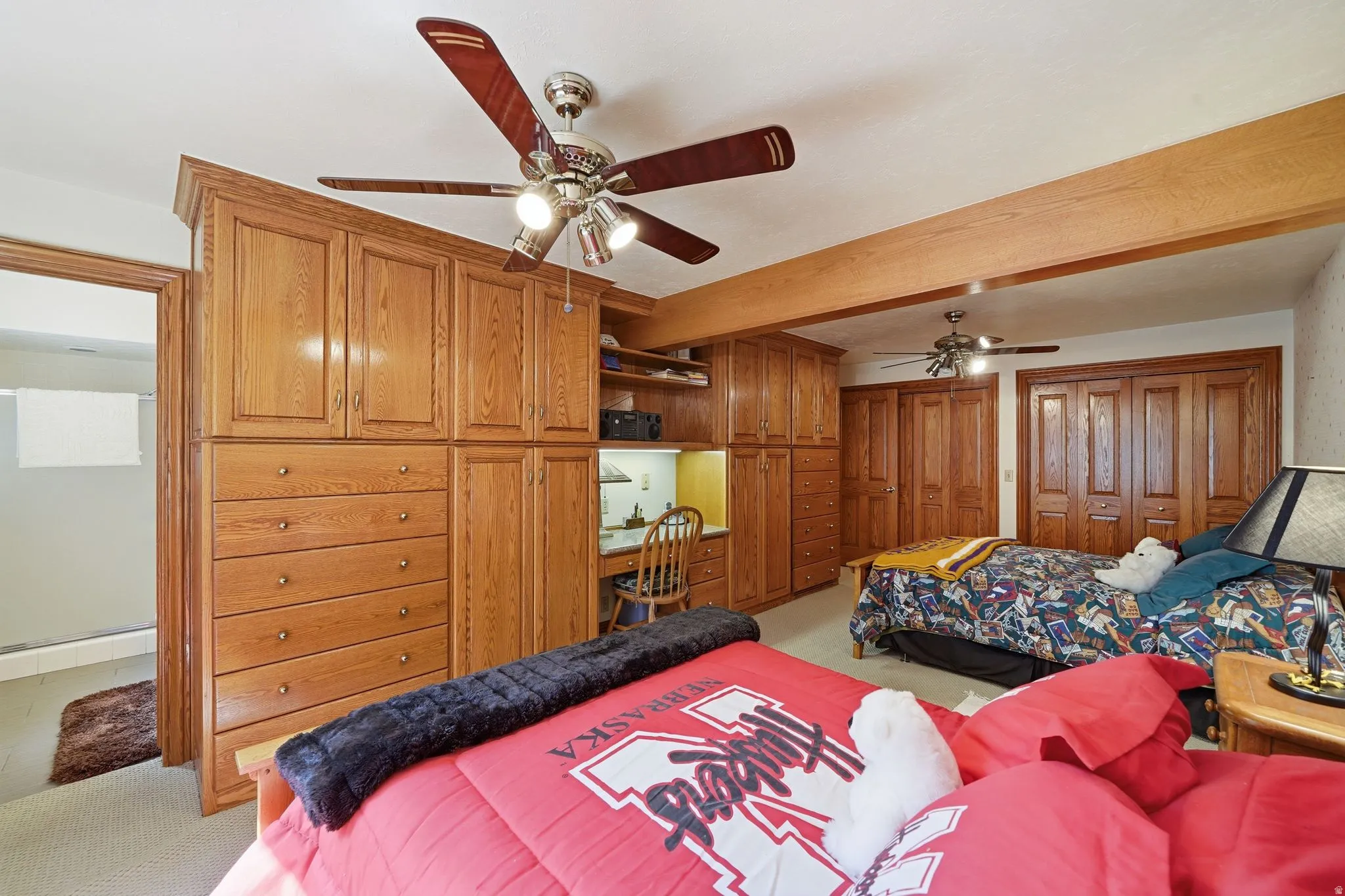 Room featuring extensive built-in wood cabinetry, integrated desk space, and two ceiling fans with lighting