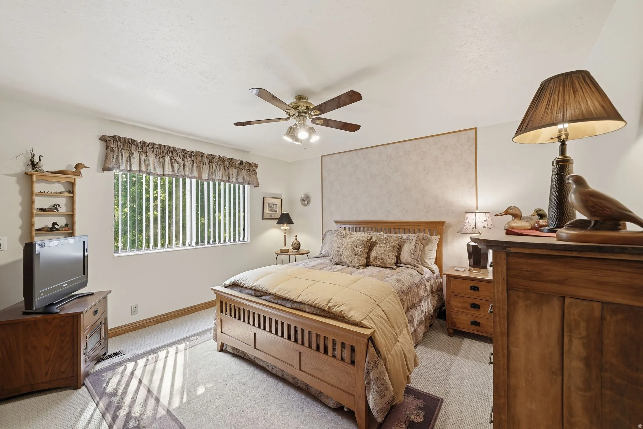 Carpeted room featuring a ceiling fan with integrated lighting, a large window with vertical blinds, a decorative valance, and neutral wall tones