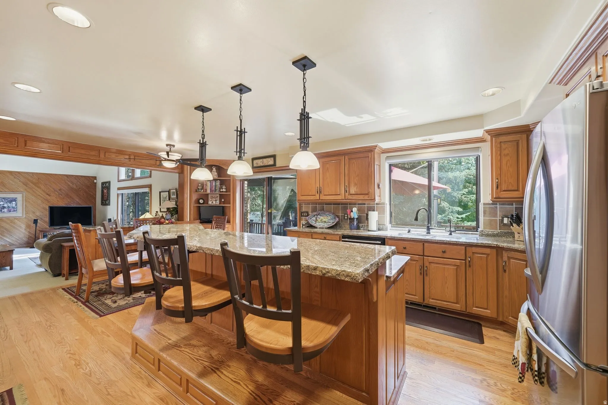 Kitchen featuring wood-finish flooring, wood cabinetry, stone countertops, and a stainless steel refrigerator