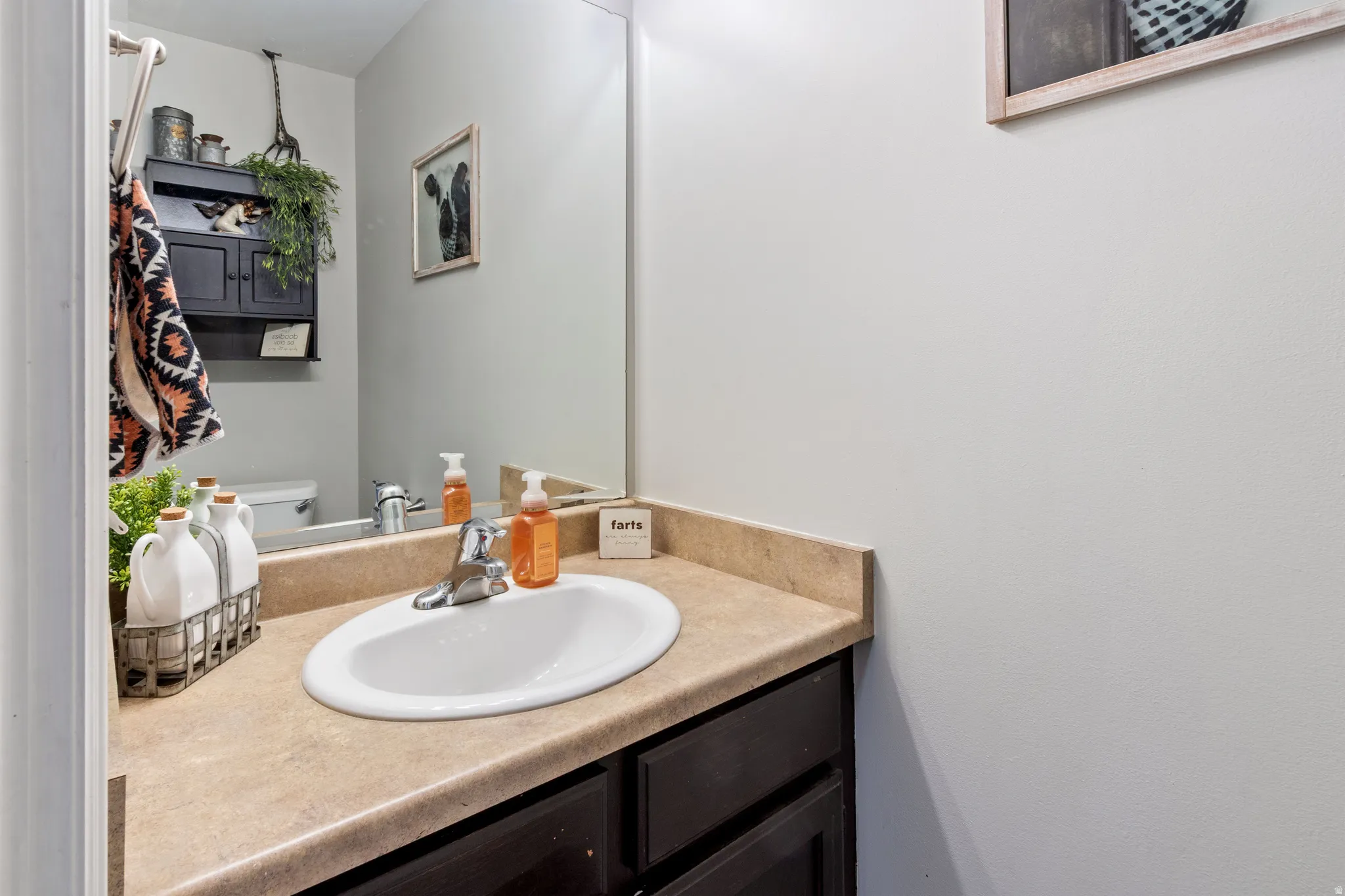 Vanity with integrated sink, laminate countertop, and dark wood-finish cabinetry