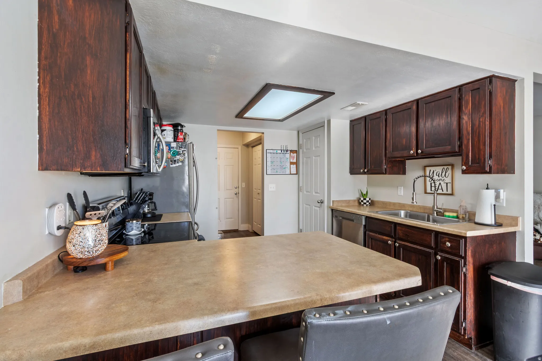 Spacious kitchen featuring rich wood cabinetry, a double basin stainless steel sink, and a built-in dishwasher