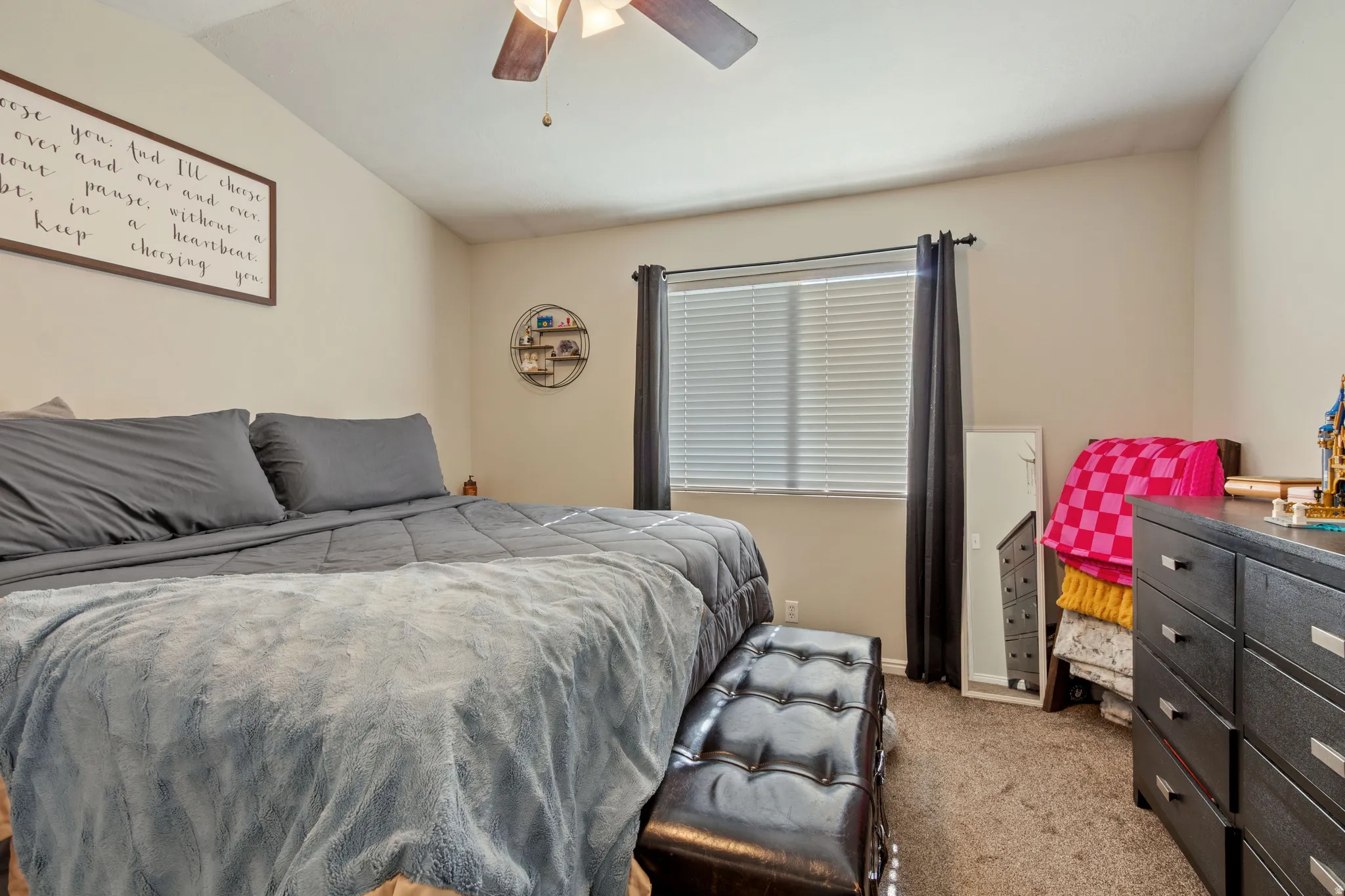 Spacious bedroom featuring neutral wall tones, textured carpet, and a ceiling fan with integrated lighting