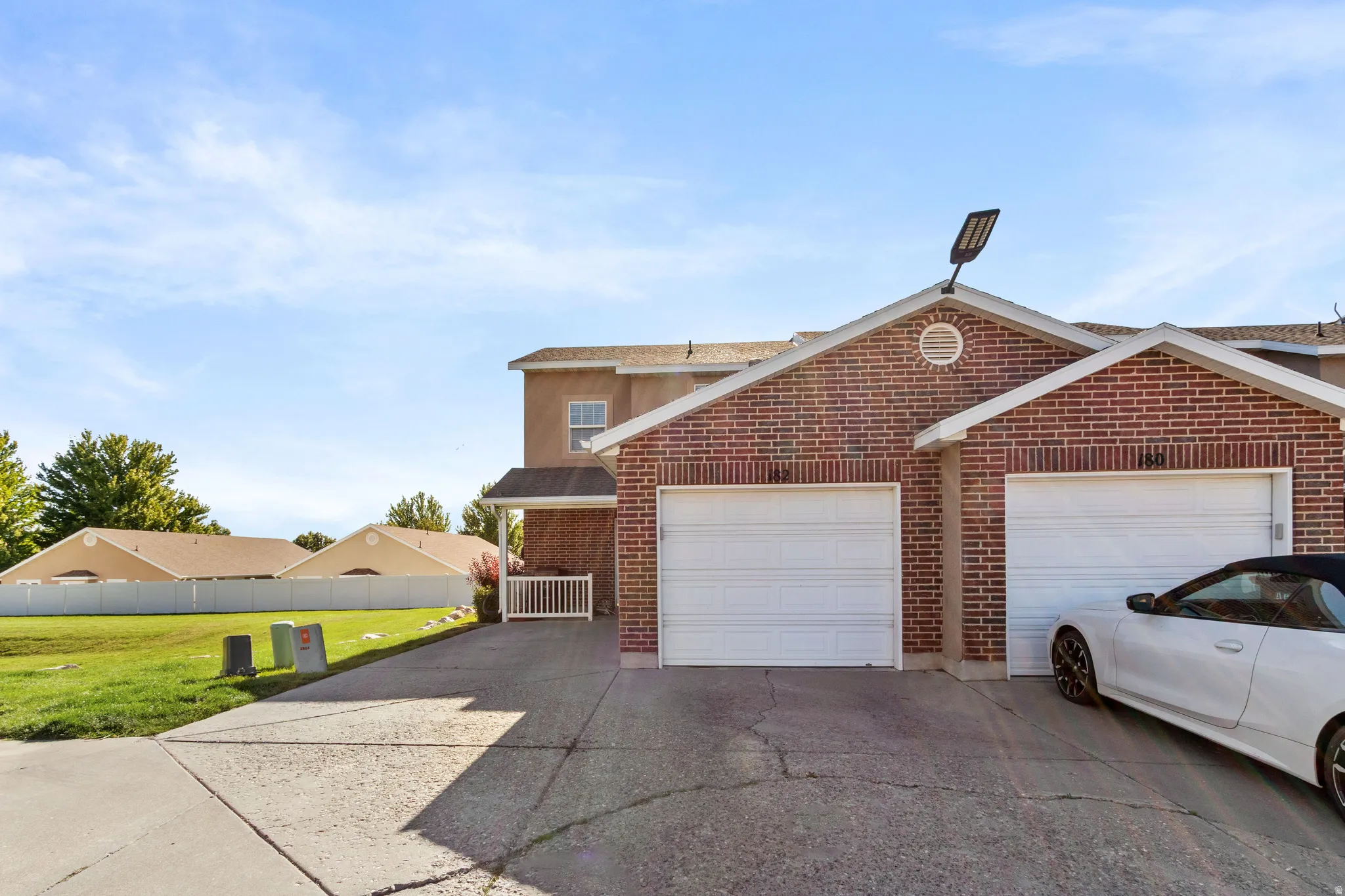 Brick exterior with two individual garage doors, dedicated driveway, covered entryway, and a manicured lawn