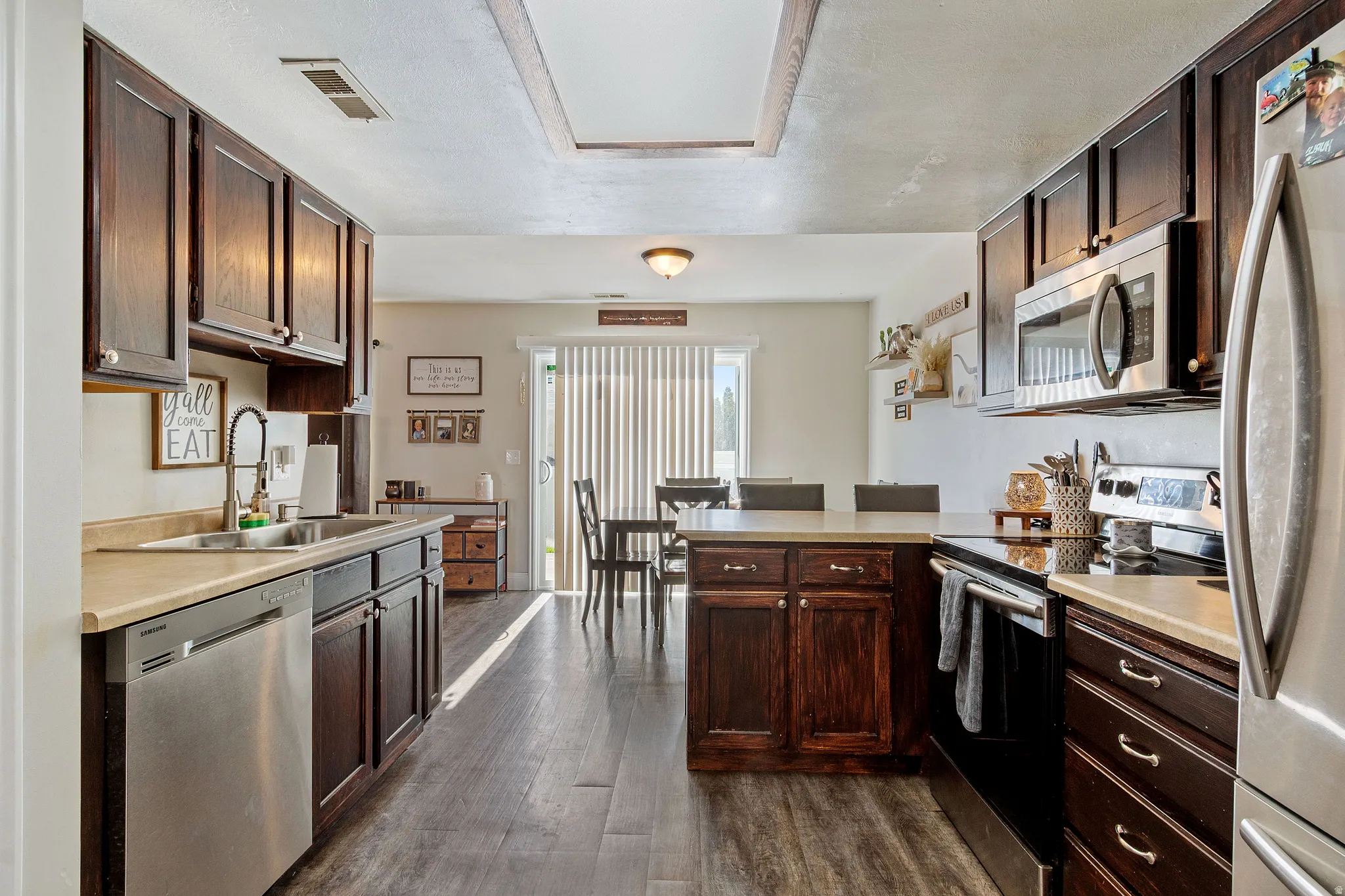 Kitchen featuring dark wood cabinetry, light countertops, and stainless steel appliances