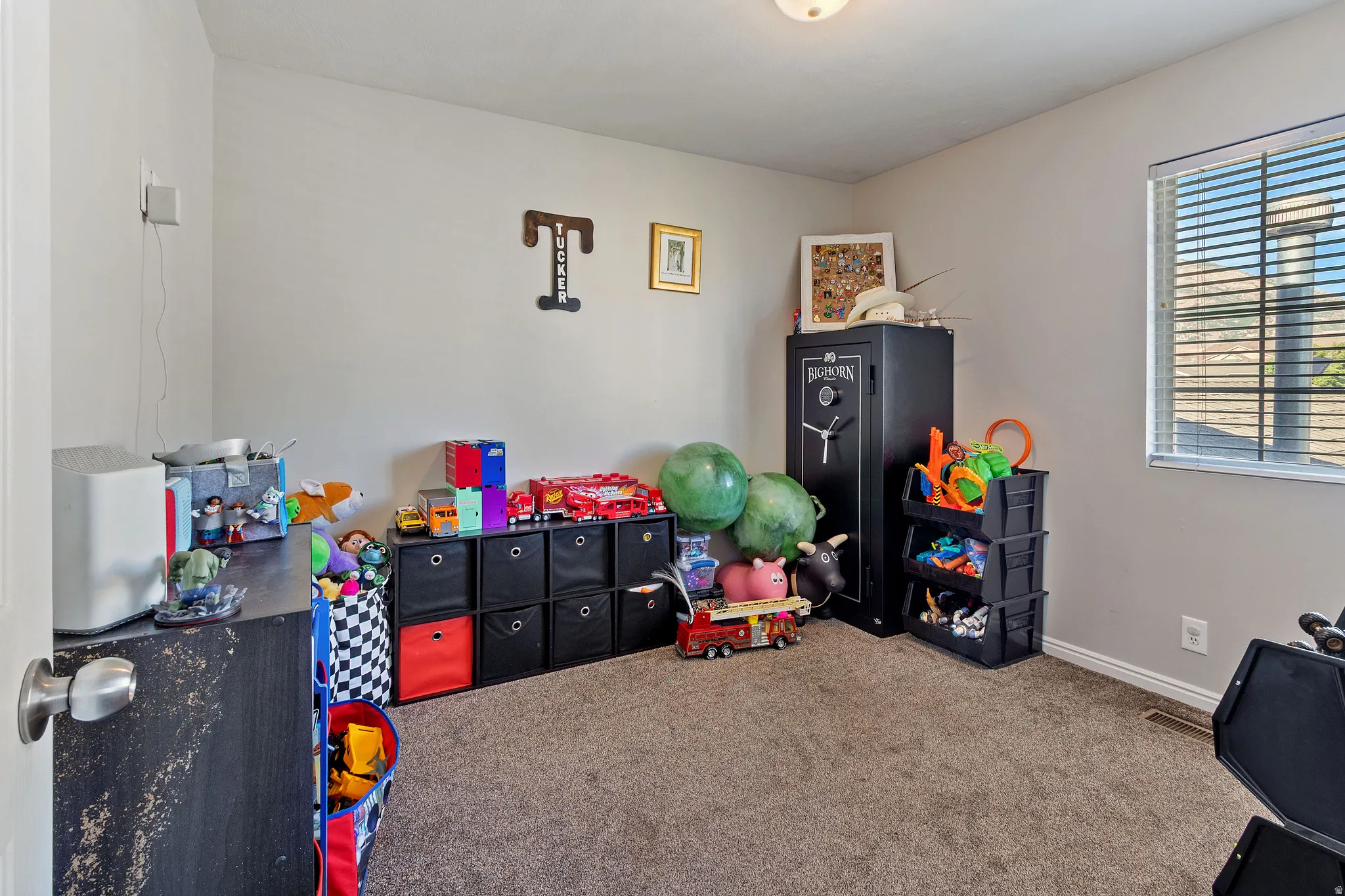 Carpeted interior room with neutral wall tones and a single window with blinds