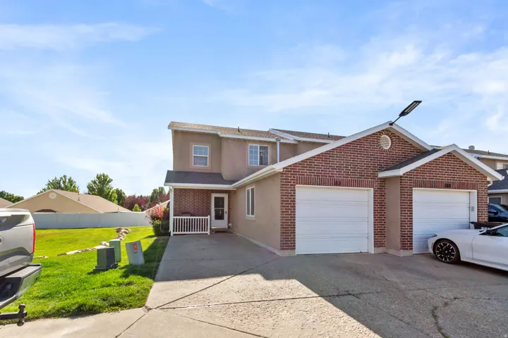 Brick and stucco exterior featuring two attached single-car garages with white overhead doors