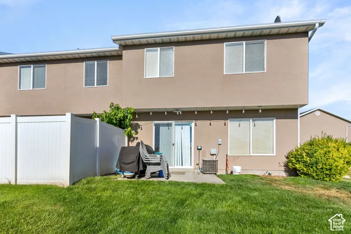 Expansive backyard featuring a manicured lawn, a concrete patio, and a white privacy fence